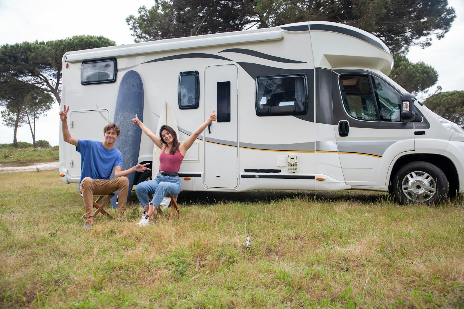 Happy couple relaxing by camper van in sunny campsite, Portugal.